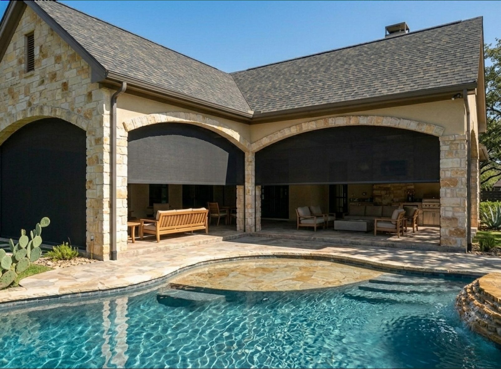 Flower Mound arched stone patio with motorized exterior screens deployed, viewed from across the pool