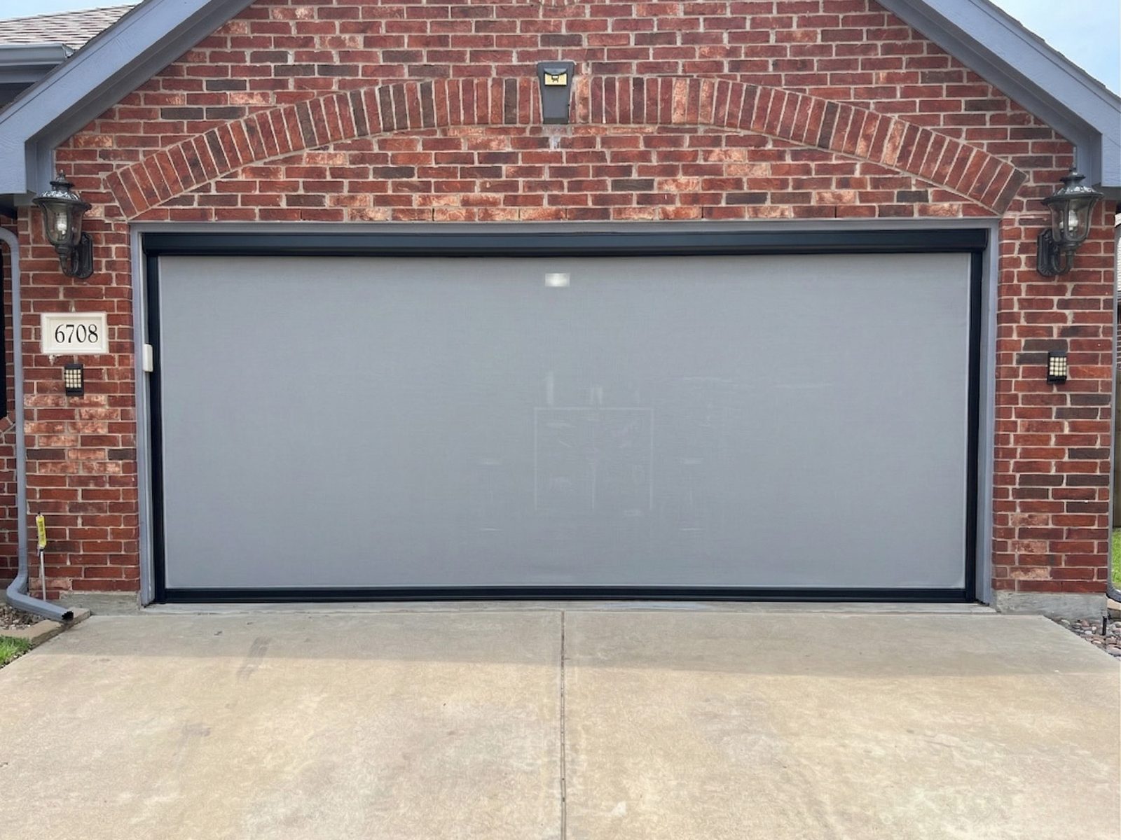 Motorized garage screen fully closed on brick home in Fort Worth