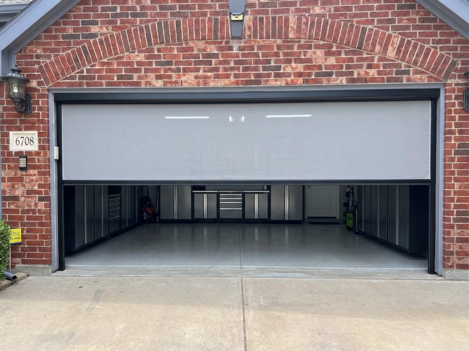 Motorized garage screen partially open showing interior in Fort Worth