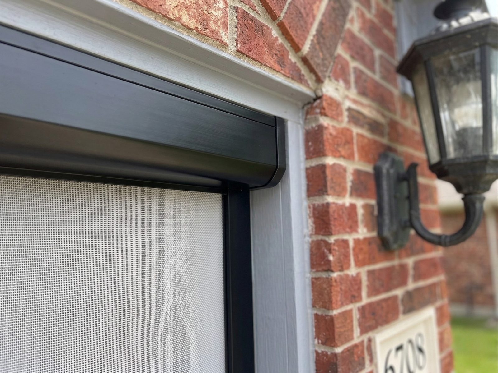 Close-up of screen housing hardware on brick home in Fort Worth Texas